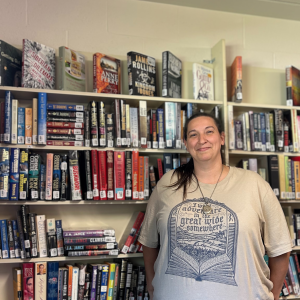 Alecia posing in front of bookshelves in the Thrift Store.